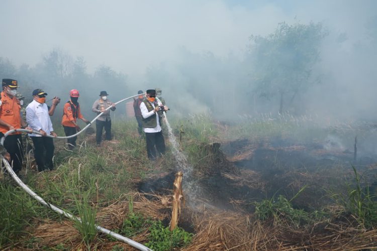 Gubernur Kalsel H. Muhidin menyemprotkan air ke titik api saat meninjau kebakaran hutan dan lahan di kawasan Guntung Damar, Ring 1 Bandara Internasional Syamsudin Noor, Banjarbaru.